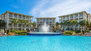 Un hôtel doté d’une piscine centrale, de palmiers et d’une fontaine.