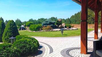 A paved pathway leading to a gazebo with a view of a landscaped garden and distant buildings.