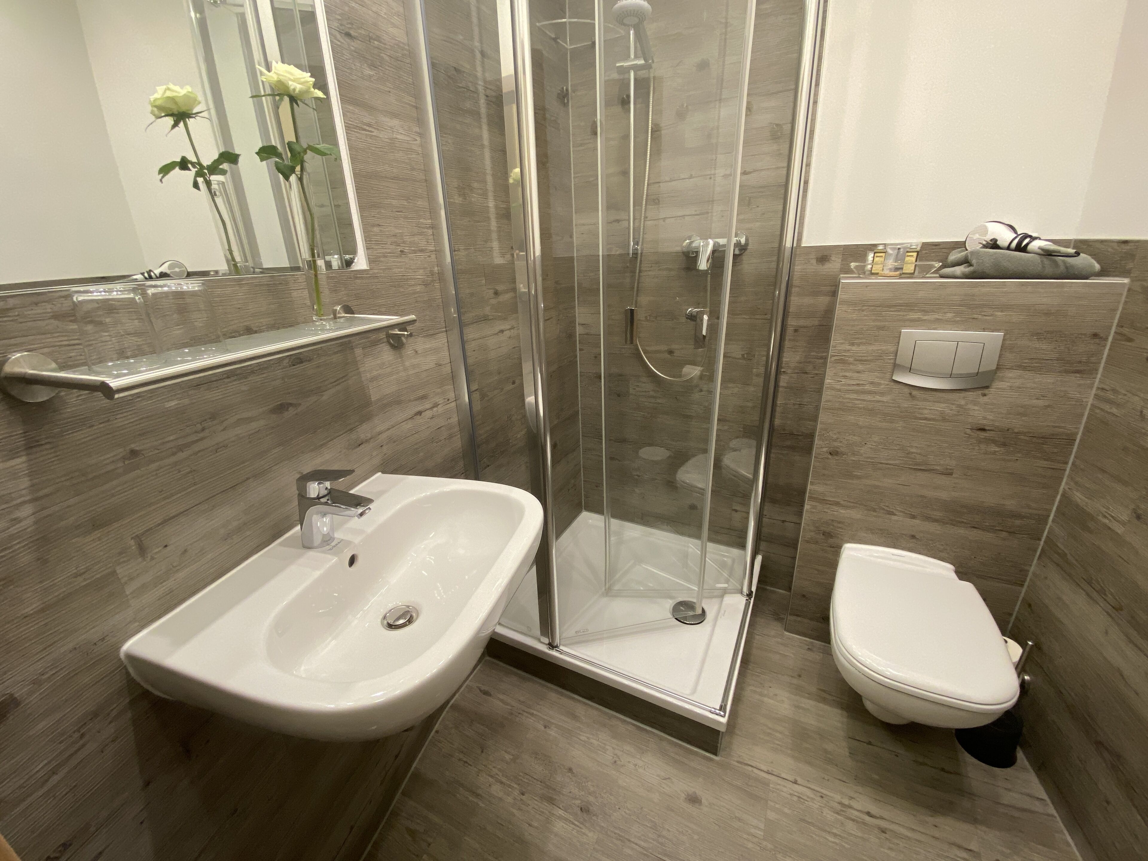 A modern bathroom with a glass-enclosed shower, a white sink, and a toilet.