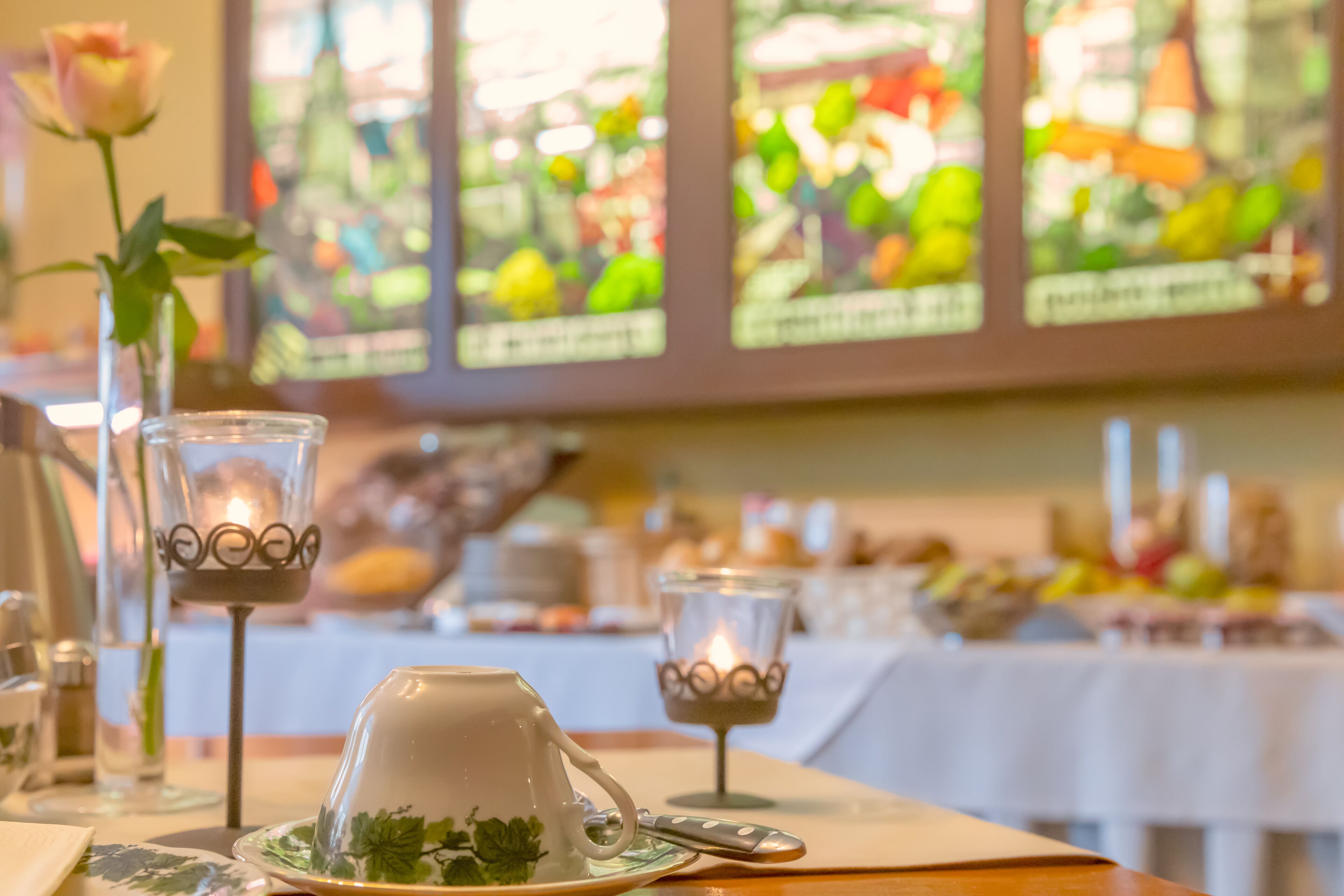 A dining table with a teapot, cups, and a candle holder.