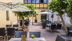 Een terras met tafels, stoelen, parasols en plantenpotten.