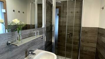 A modern bathroom with a glass-enclosed shower, a white sink, and a large mirror.