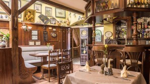 Een gezellig restaurant met houten inrichting, een bar en een zithoek met een bank en tafels.