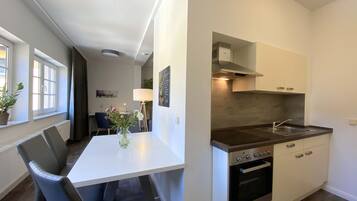 A modern kitchen with white cabinetry, a built-in oven, and a stainless steel sink.