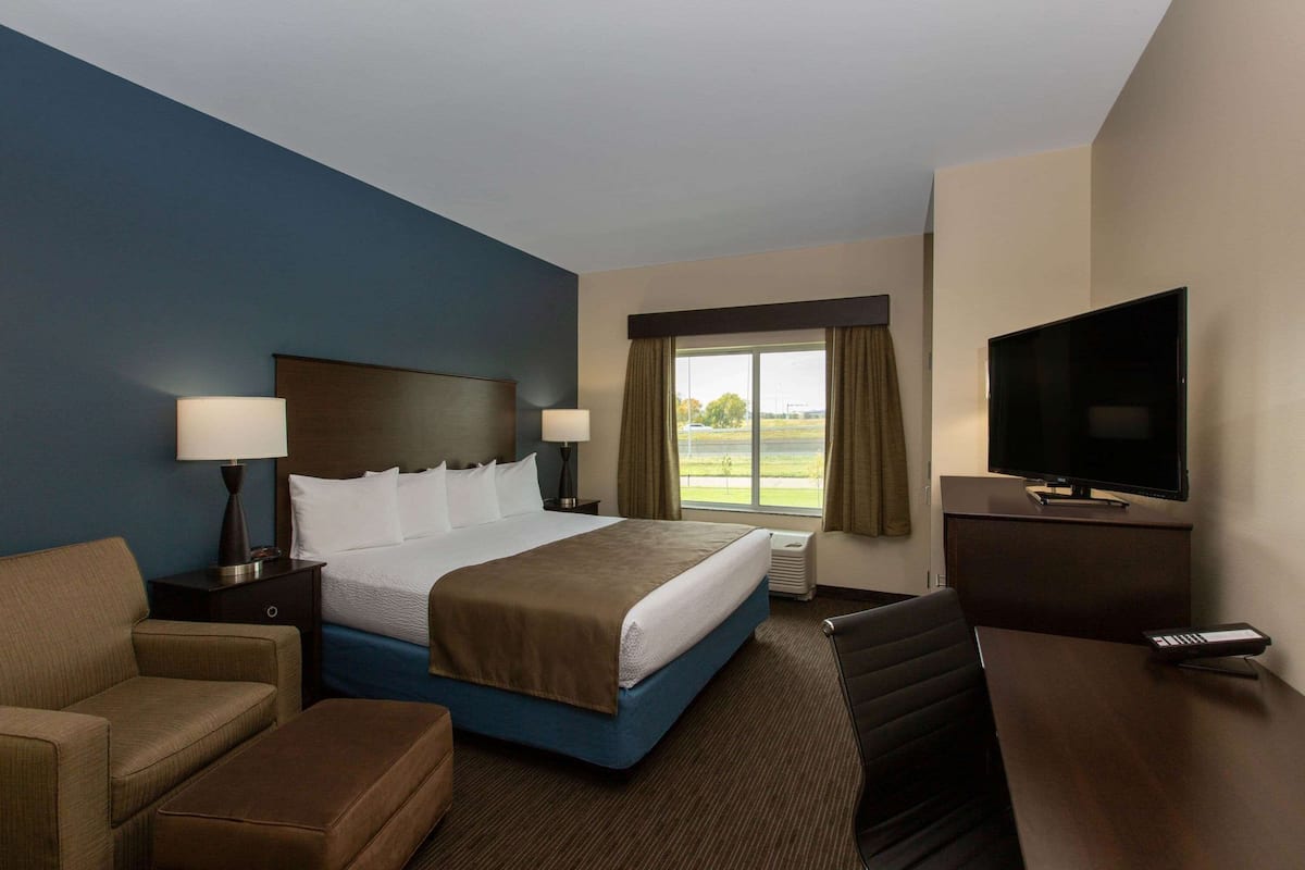 Habitación de hotel con una cama grande, un escritorio, un televisor y vistas al exterior.