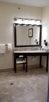 Un baño con un espejo grande, un lavabo y un perchero para toallas.