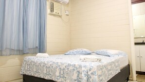 A room with a bed, a window with curtains, an air conditioning unit, and a door. - Hospedaria Gebel LocDay (Recife)