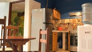 A compact kitchen with a refrigerator, stove, and wooden cabinets. - Casa Caballito (León)