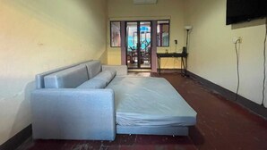 A room with a sofa, a TV mounted on the wall, and a door leading to an outdoor area. - Casa Caballito (León)