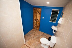 A small bathroom with a wooden door, a white toilet, and a sink. - Casa Caballito (León)