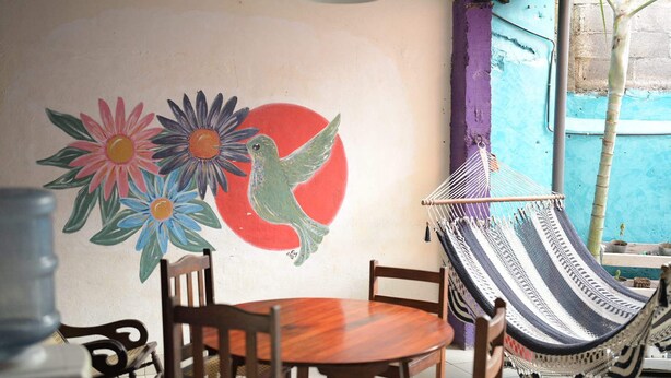 A room with a hammock, a table, chairs, and a wall mural. - Casa Caballito (León)