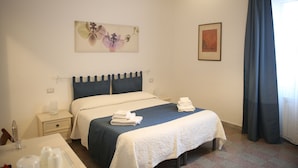 A hotel room with a bed, bedside tables, a desk, and a lamp. - Corso Messina (Crotone)