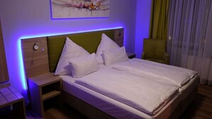A neatly made bed with white linens, a green headboard, and a bedside table with a lamp. - Minx - Cityhotels (Aachen)