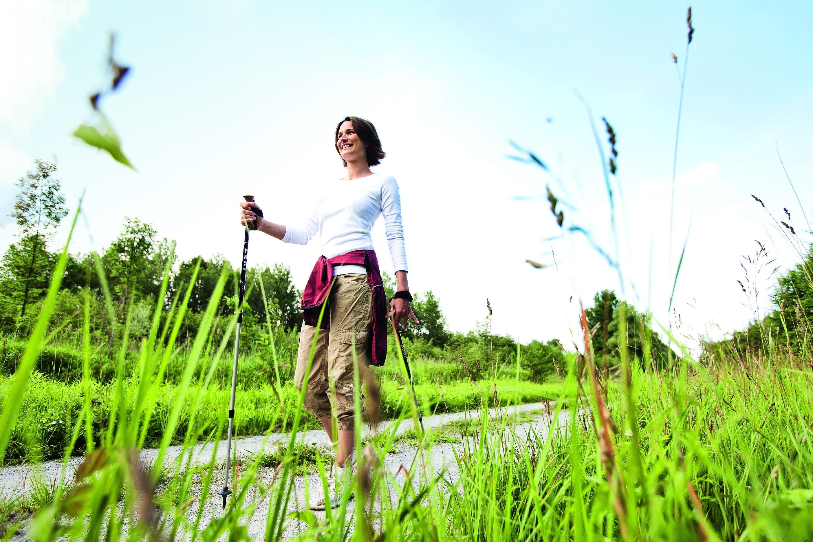 A person walking in a grassy area with a path.
