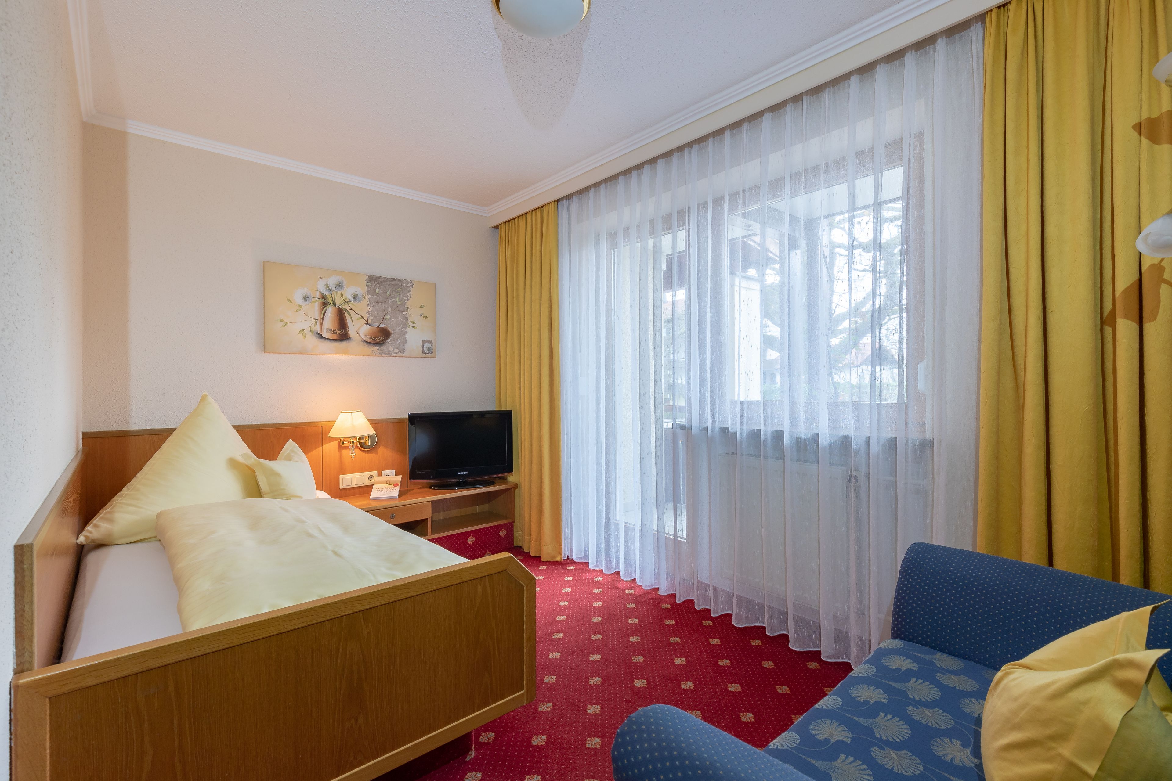 Une chambre d’hôtel avec un lit, une télévision, un canapé et un tableau au mur.