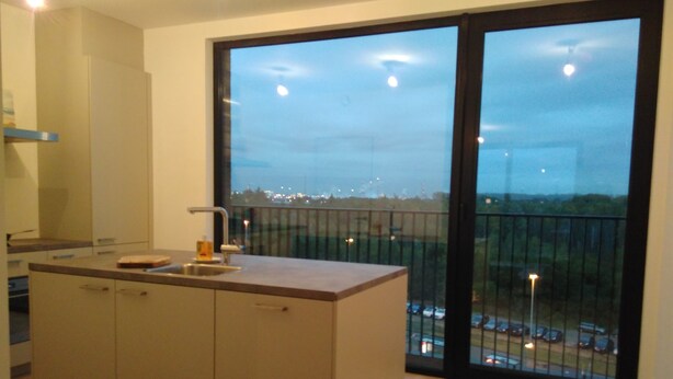 A modern kitchen with a large window and a view of a cityscape. - Fully Equipped Sunny Apartment (Antwerp)