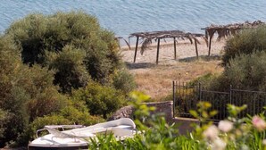 Une vue sur la côte, avec une plage, une pergola en bois et un bateau.