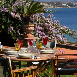 A table set outdoors with plates, glasses, and a pitcher, surrounded by chairs and a potted plant. - Sapphire Mansion (Karystos)