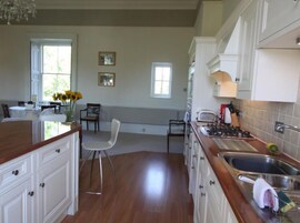 A kitchen with wooden cabinets, a stainless steel sink, and a dining area with a table and chairs.