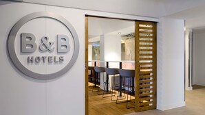 Skilt for et Bed & Breakfast hotel, en træafskærmning med et moderne design, og et barområde med barstole.
