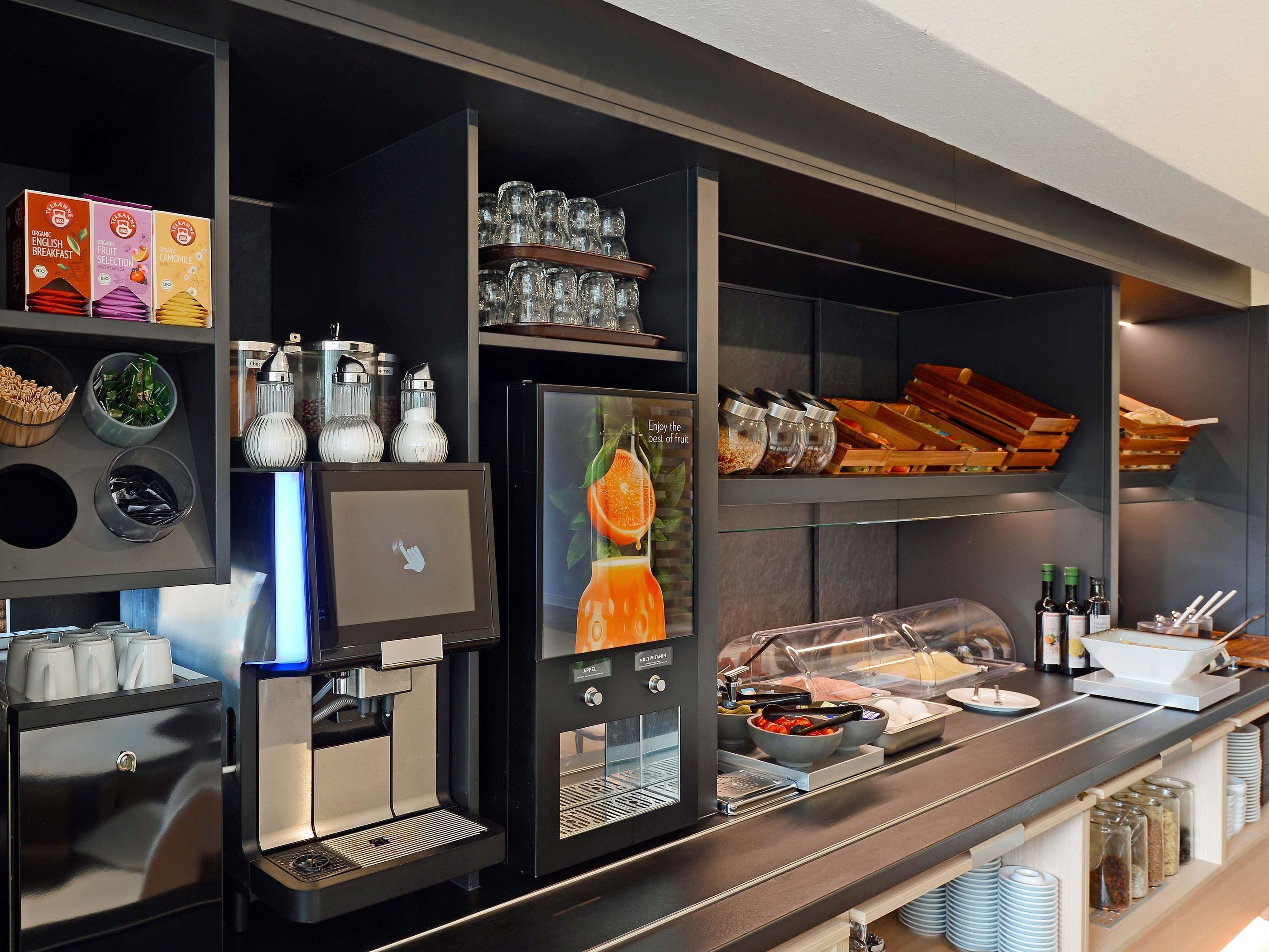 Un bar pour le petit-déjeuner équipé d’une machine à café, de verres et de divers aliments.