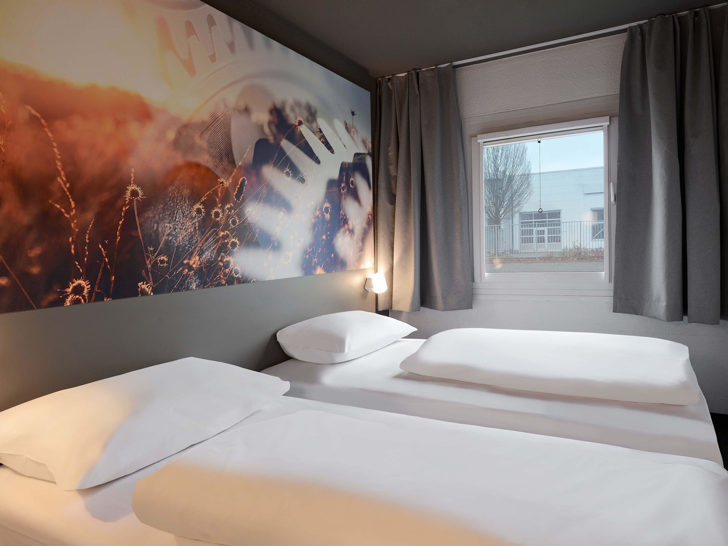 Ein Hotelzimmer mit einem großen Bett, Blick ins Freie und einer Wand mit floralem Wandbild.