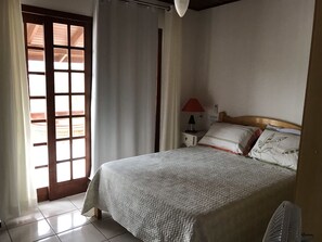 A bedroom with a bed, a nightstand, a lamp, and a window with curtains.