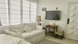 Een moderne woonkamer met een bank, een televisie, een lamp en een bijzettafeltje.