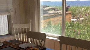 A dining table set with white plates, a fruit bowl, and woven placemats. - Sunny Beachfront Cottage with Spectacular Ocean Views  (Saco)