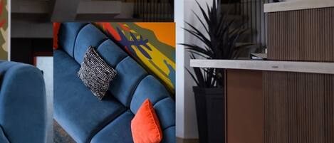 A modern interior with a staircase, a blue sofa with patterned cushions, and a round white table with a decorative object.