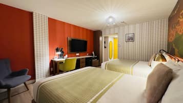 Una habitación de hotel con dos camas, un escritorio con silla, un televisor y un espejo.