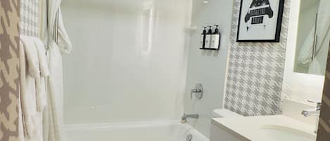 A modern bathroom with a bathtub, toilet, and vanity.