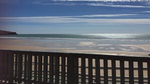 Une plage avec une clôture en bois au premier plan, un ciel dégagé et une mer calme.
