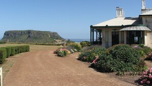Un bâtiment doté d’un jardin et d’un chemin qui mène à une structure surmontée d’un toit en métal et soutenue par des colonnes.