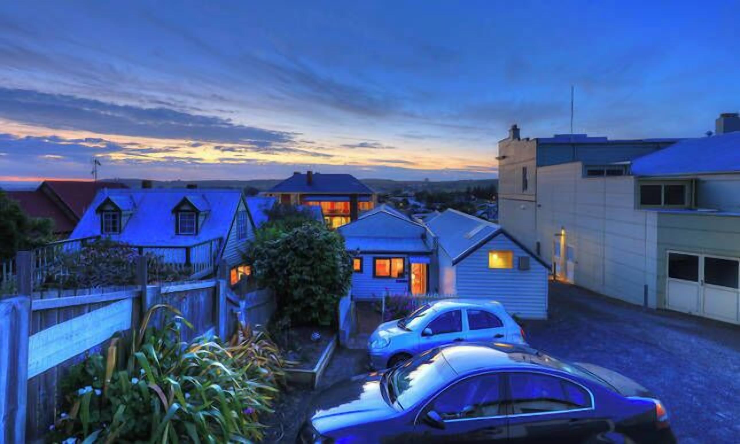 A residential area with houses and parked cars during twilight.