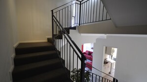 Una escalera con barandillas negras que baja a un nivel inferior.