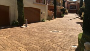 Un camino pavimentado que lleva a un edificio con escaleras y un pequeño jardín.
