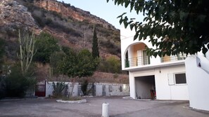 A building with a white exterior, a balcony, and a garage entrance.