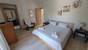 Una habitación de hotel con una cama grande, una silla, una mesita de noche y un espejo.
