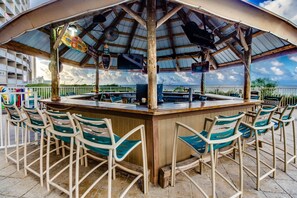 Relax with a refreshing drink at the outdoor bar, surrounded by comfortable seating and a shaded area.
