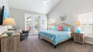A bedroom with a bed, a dresser, a nightstand, a ceiling fan, and a view of the outdoors. - Large outdoor summer kitchen, Private Pool, Theatre Room, 2 miles to Disney ! (Kissimmee)