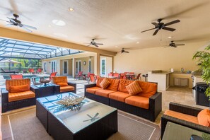 A spacious indoor area with a pool, outdoor seating, ceiling fans, and a kitchen area. - Large outdoor summer kitchen, Private Pool, Theatre Room, 2 miles to Disney ! (Kissimmee)