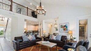 A spacious living room with a high ceiling, a chandelier, and a view of the kitchen. - Large outdoor summer kitchen, Private Pool, Theatre Room, 2 miles to Disney ! (Kissimmee)