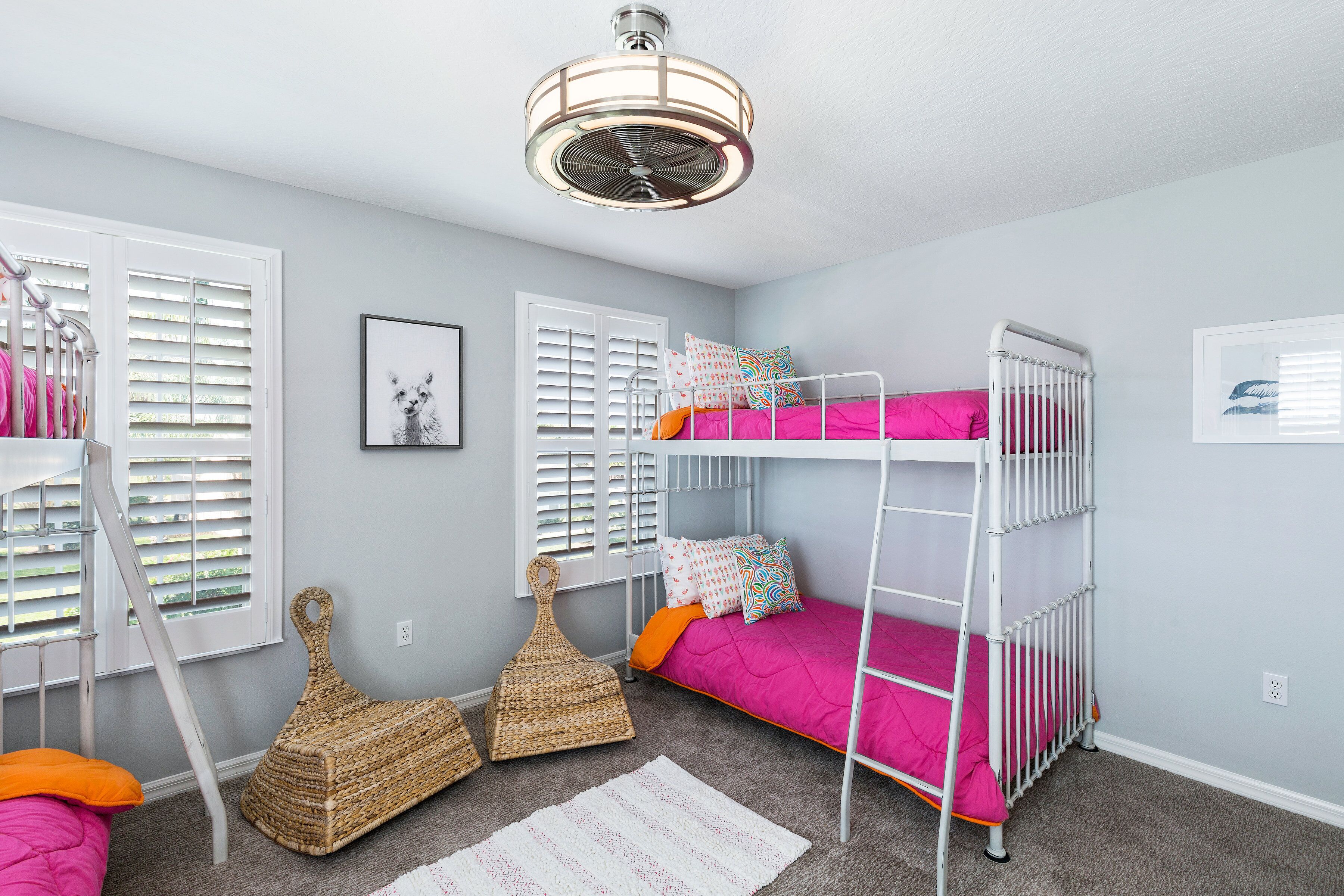 A child's room with bunk beds, a ceiling fan, and a window with blinds.