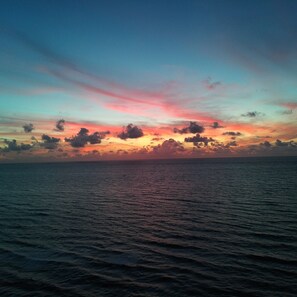 Um pôr do sol sobre um mar calmo, com horizonte límpido.