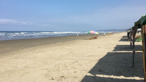Een strand met heldere lucht, een zandstrand en parasols.