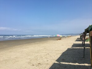 A beach with a clear sky, a sandy shore, and umbrellas.
