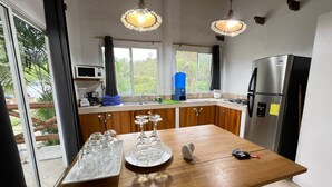 Een moderne keuken met houten kastjes, een roestvrijstalen koelkast en een groot kookeiland met glazen servies.