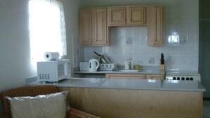 A kitchen with wooden cabinets, a microwave, a toaster, and a stove.
