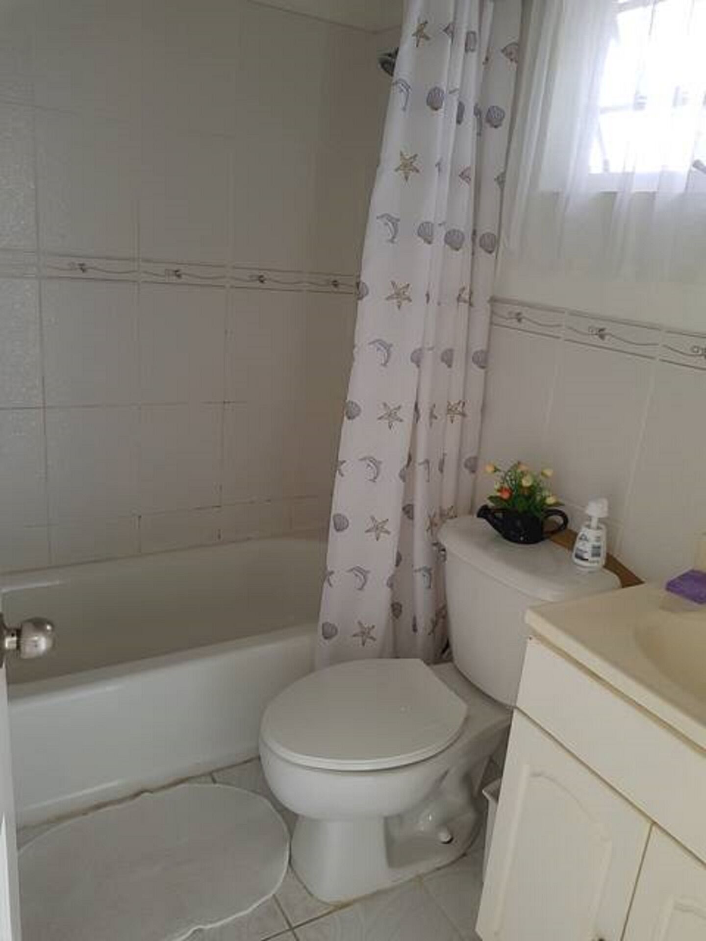 A bathroom with a toilet, bathtub, and a shower curtain with a starfish pattern.